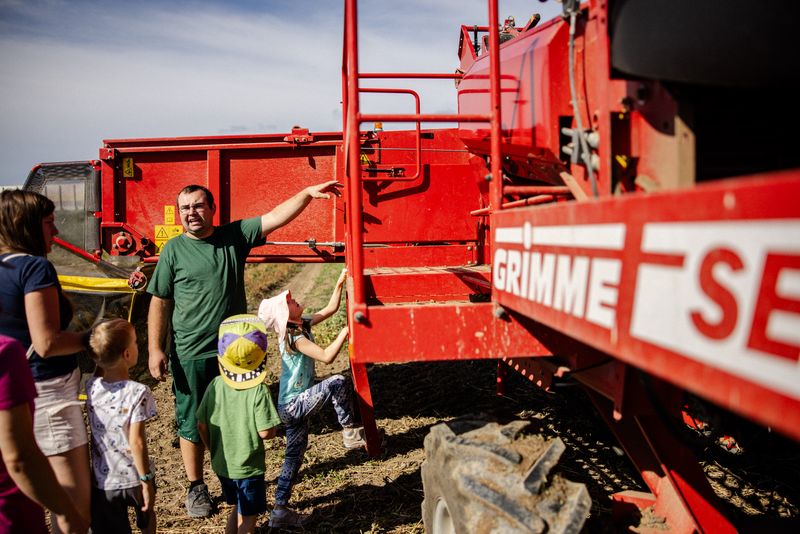 Kinder und Erwachsene bei einem roten Erdäpfelroder am Feld