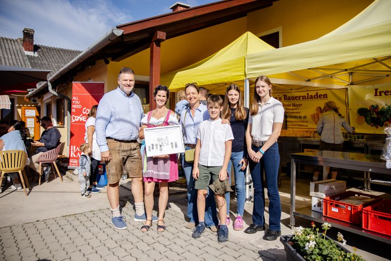 Gratulanten mit Urkunde vor dem Bauernladen