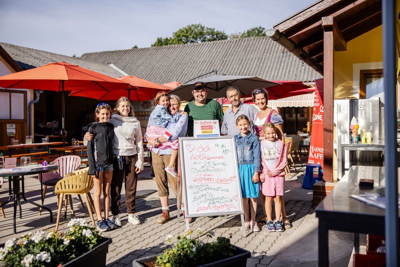 Gruppe von Erwachsenen und Kindern vor dem Bauernladen mit einer Kreidetafel